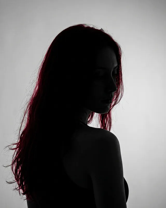 Silhueta de uma mulher de cabelo vermelho, em contraluz, de costas para a câmera.